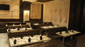 A restaurant with leather booths and tables, each set with cutlery and napkins. - Beacon T2 Mumbai (Mumbai)