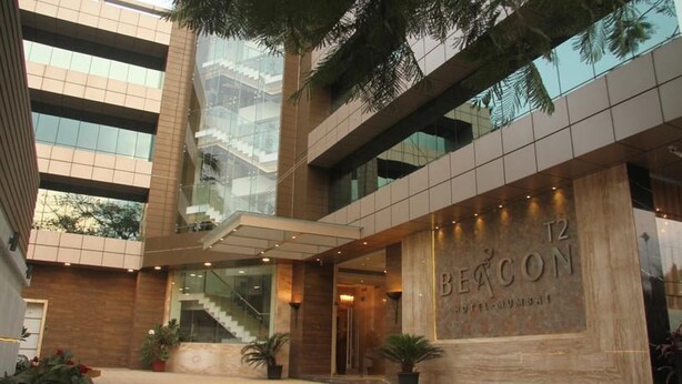 A modern hotel with a glass facade, a prominent entrance, and a staircase leading to the upper floors. - Beacon T2 Mumbai (Mumbai)