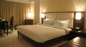 Une chambre d’hôtel avec un grand lit, une chaise, un bureau et une table de chevet.