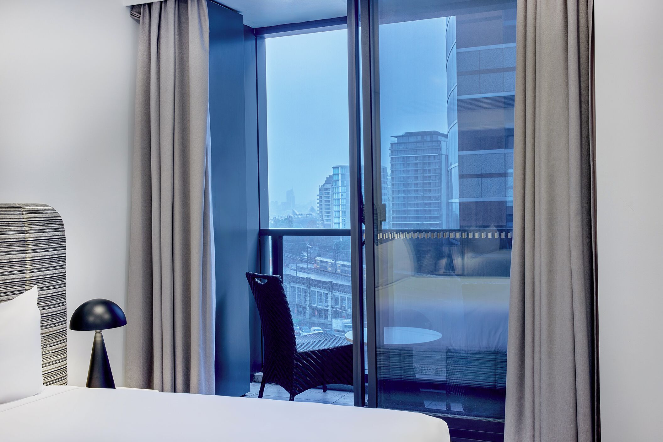 Een hotelkamer met een groot raam, een bed, een stoel en een tafel.