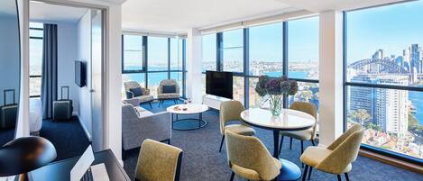 A modern hotel room with a large window, a laptop, a desk, and a seating area with a view of the city.