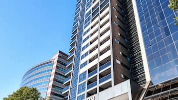 Un hotel moderno con un llamativo letrero de 'Meriton', que presenta una estructura de varios pisos con ventanas amplias y una fachada de vidrio curvado.