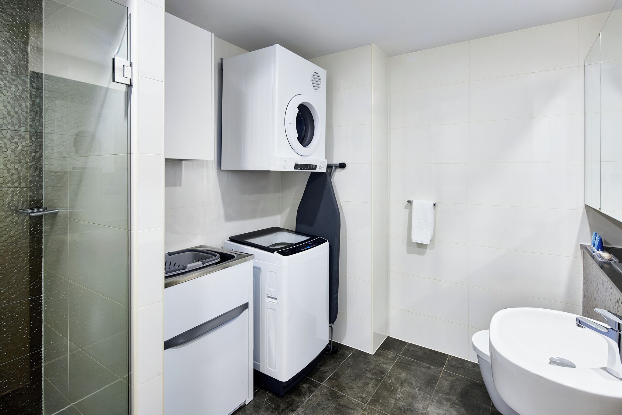 A compact bathroom with a washing machine, dryer, and a toilet.