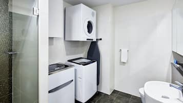 A compact bathroom with a washing machine, dryer, and a toilet.