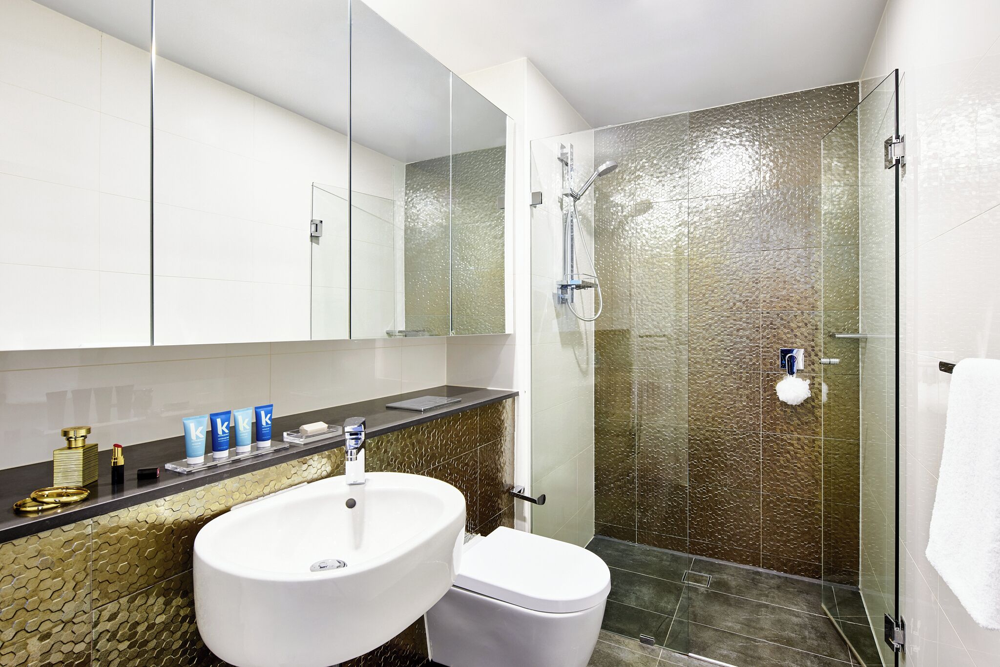 A bathroom with a glass-enclosed shower, a white sink, and a toilet.
