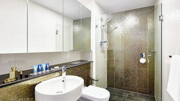 A bathroom with a glass-enclosed shower, a white sink, and a toilet.