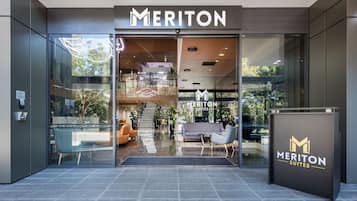 L'entrée de Meriton Suites se distingue par son design moderne, ses portes en verre et son espace d'accueil visible de l'extérieur.