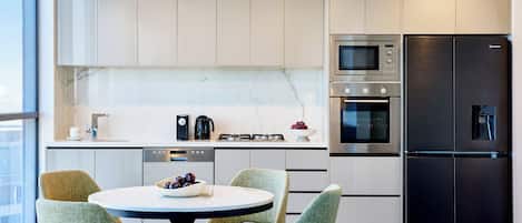 A modern kitchen with a dining area, featuring a round table, chairs, and a black refrigerator.