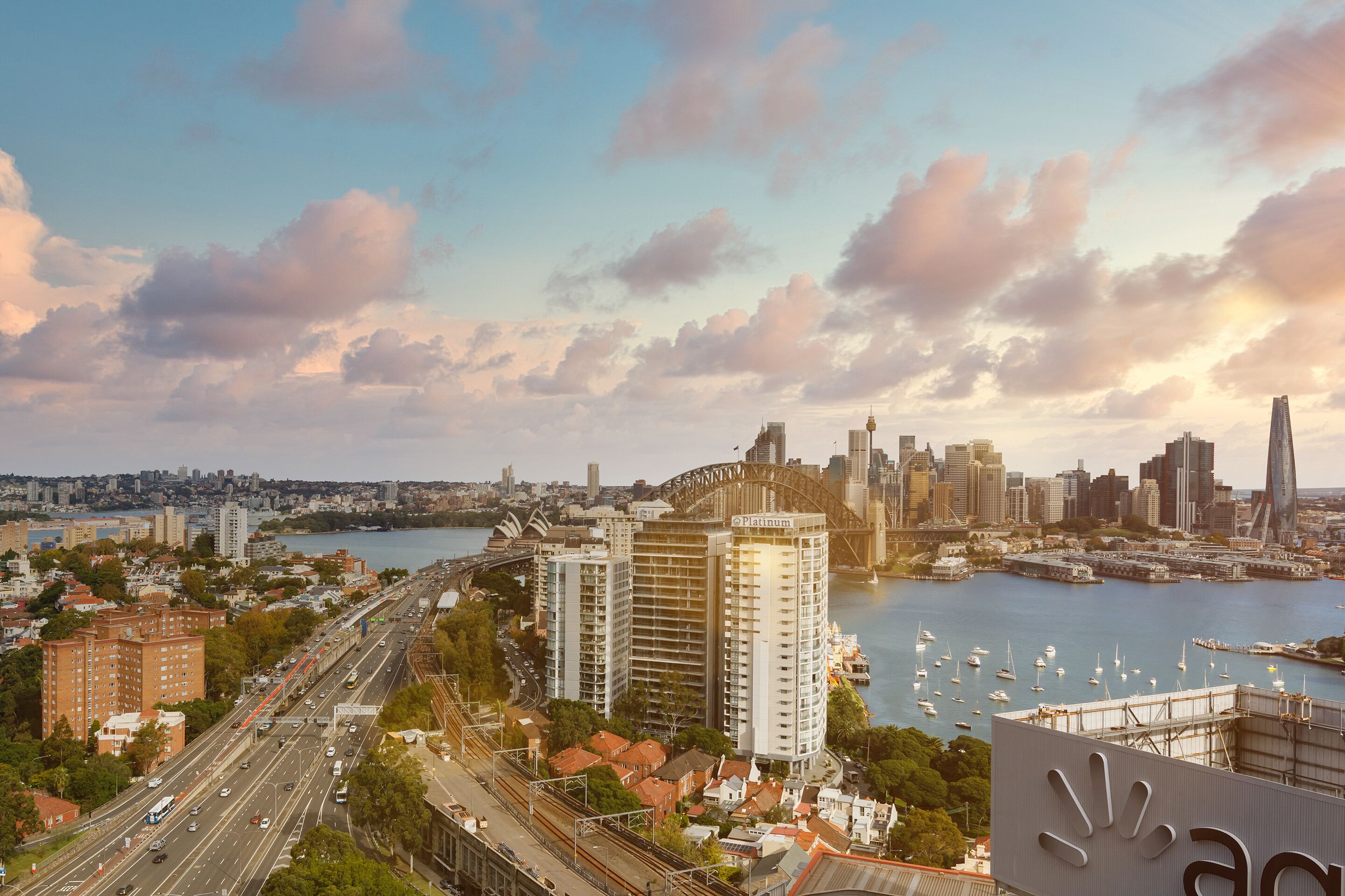 A cityscape with a prominent bridge, high-rise buildings, and a waterfront with boats.