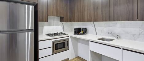A modern kitchen with a stainless steel refrigerator, a gas stove, a microwave, and a sink.