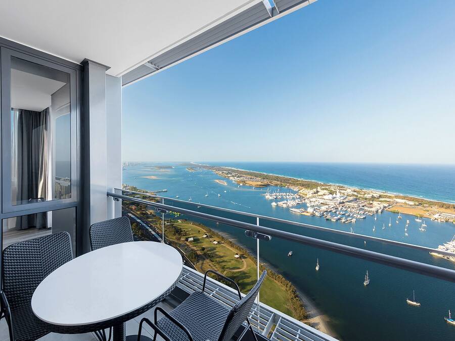 Un balcone con tavolo e sedie, con vista su un porto turistico e sulla costa.