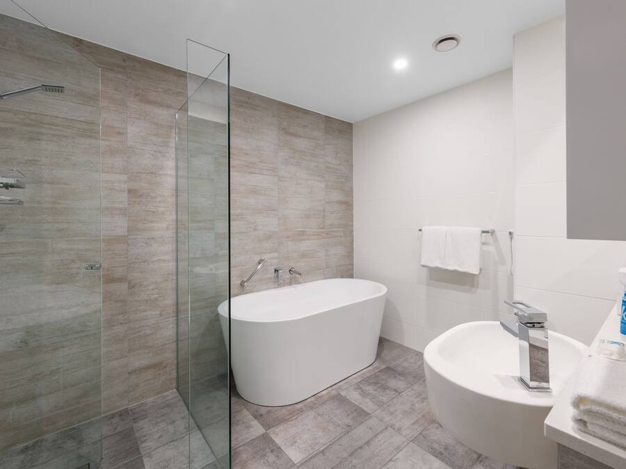 A modern bathroom with a glass-enclosed shower, a freestanding bathtub, and a sink with a mirror.