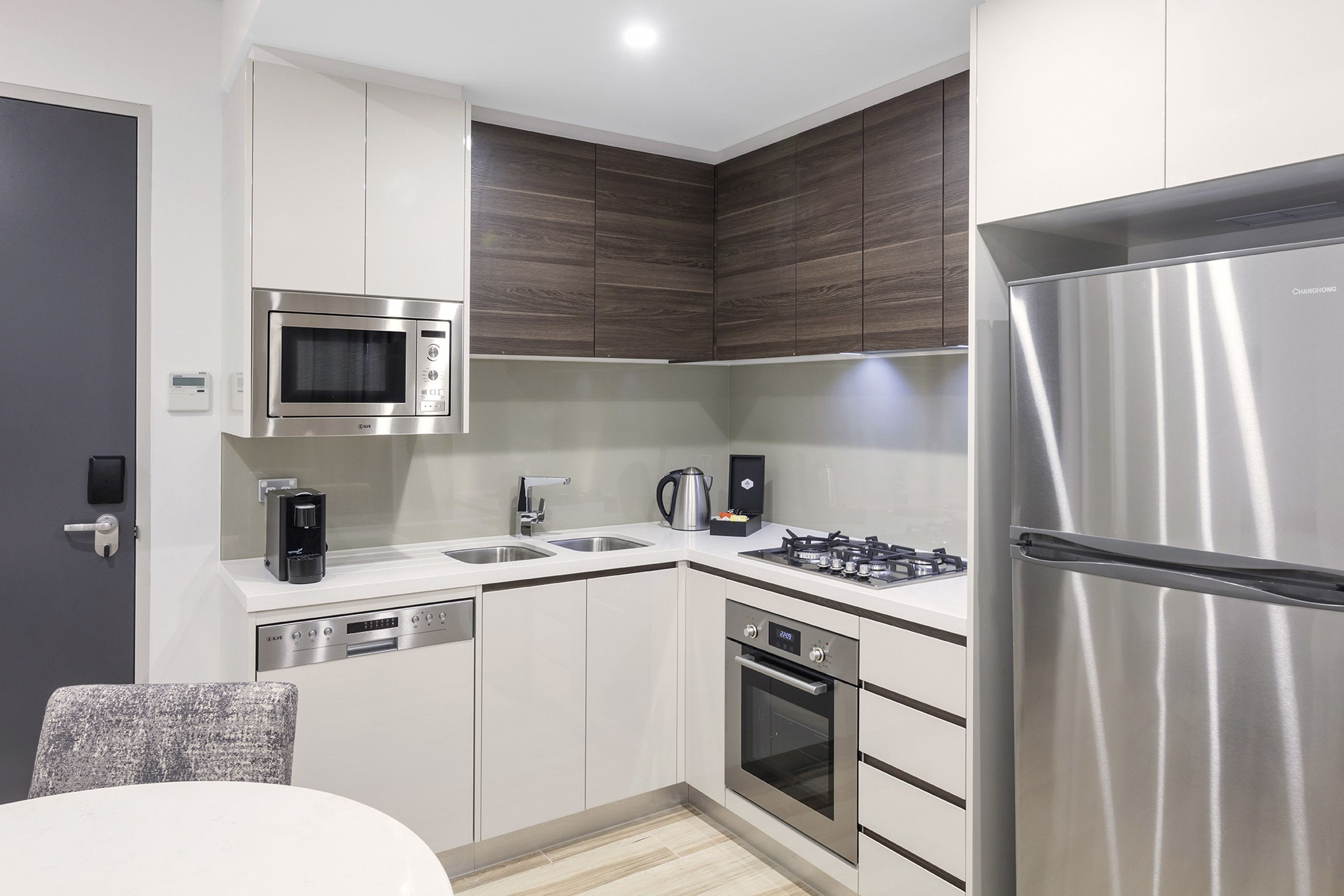 A modern kitchen with stainless steel appliances, white cabinetry, and a built-in microwave.