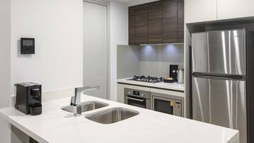 A modern kitchen with a stainless steel refrigerator, a coffee maker, and a double sink.