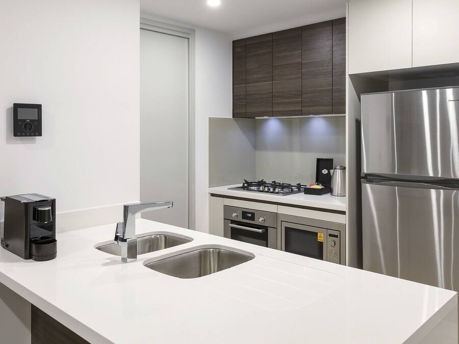 A modern kitchen with a stainless steel refrigerator, a coffee maker, and a double sink.
