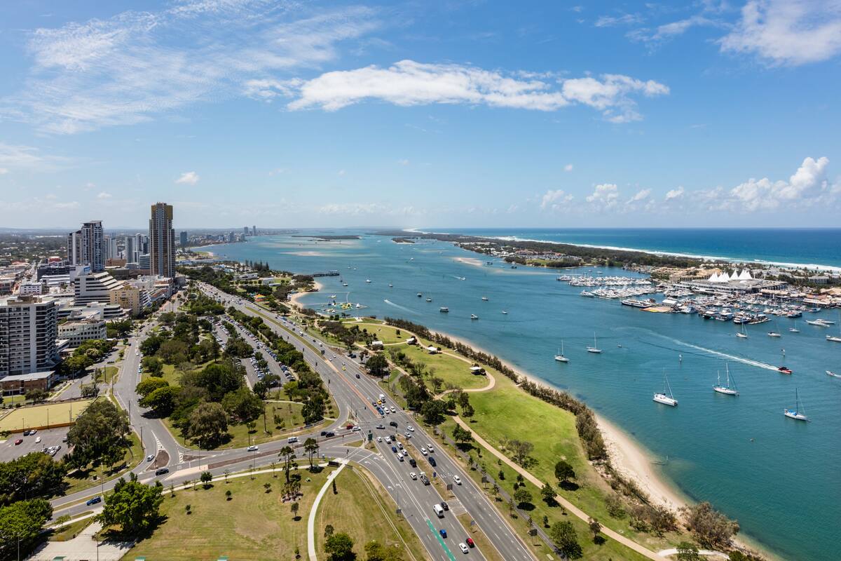 Vista aèria d'una ciutat costanera amb un port esportiu, carreteres i edificis.