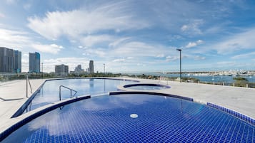 Una piscina techada, una piscina al aire libre, sombrillas