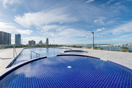Una piscina techada, una piscina al aire libre, sombrillas