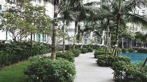 A pathway lined with lush greenery and palm trees leading to a pool area. - Holi 1Medini Suites (Iskandar Puteri)