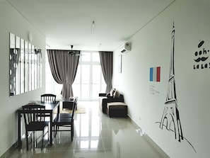 A modern living room with a dining area, large windows, and a wall mural of the Eiffel Tower. - Holi 1Medini Suites (Iskandar Puteri)