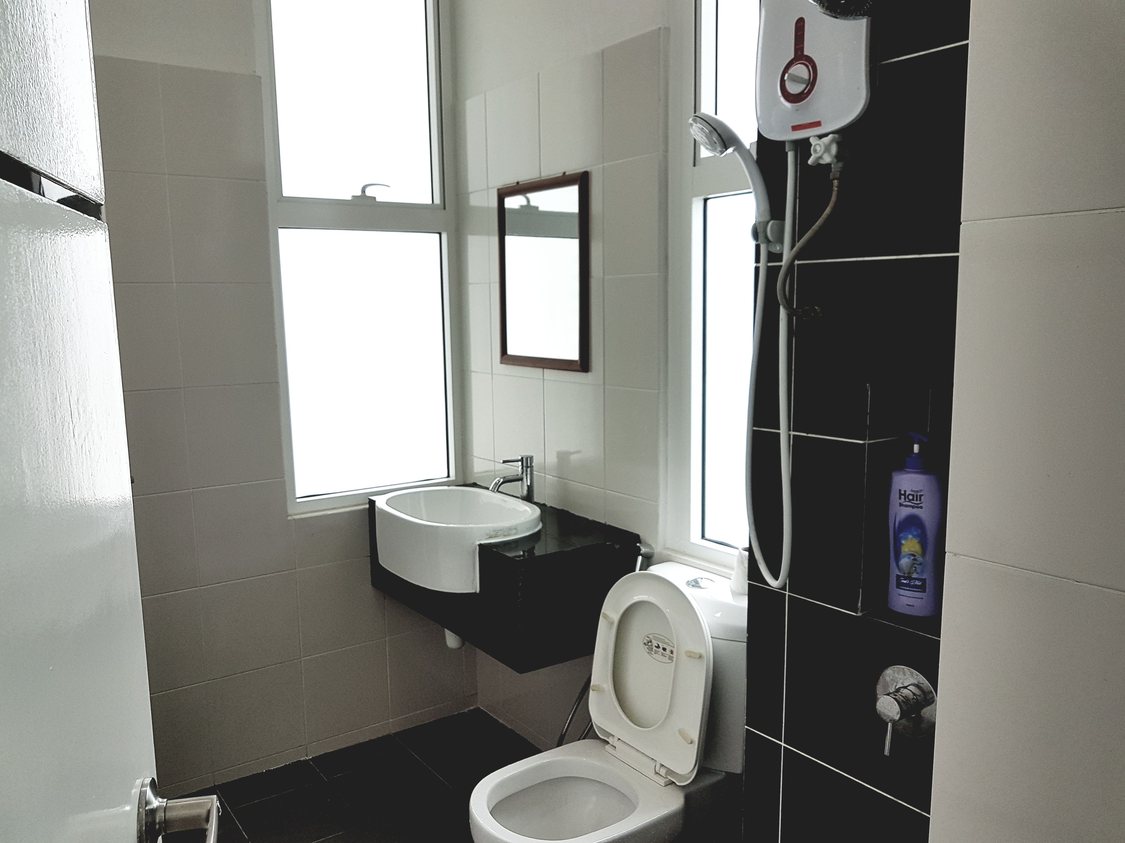 Un bagno con il water bianco, un lavandino e uno specchio. Una finestra permette l'illuminazione naturale.