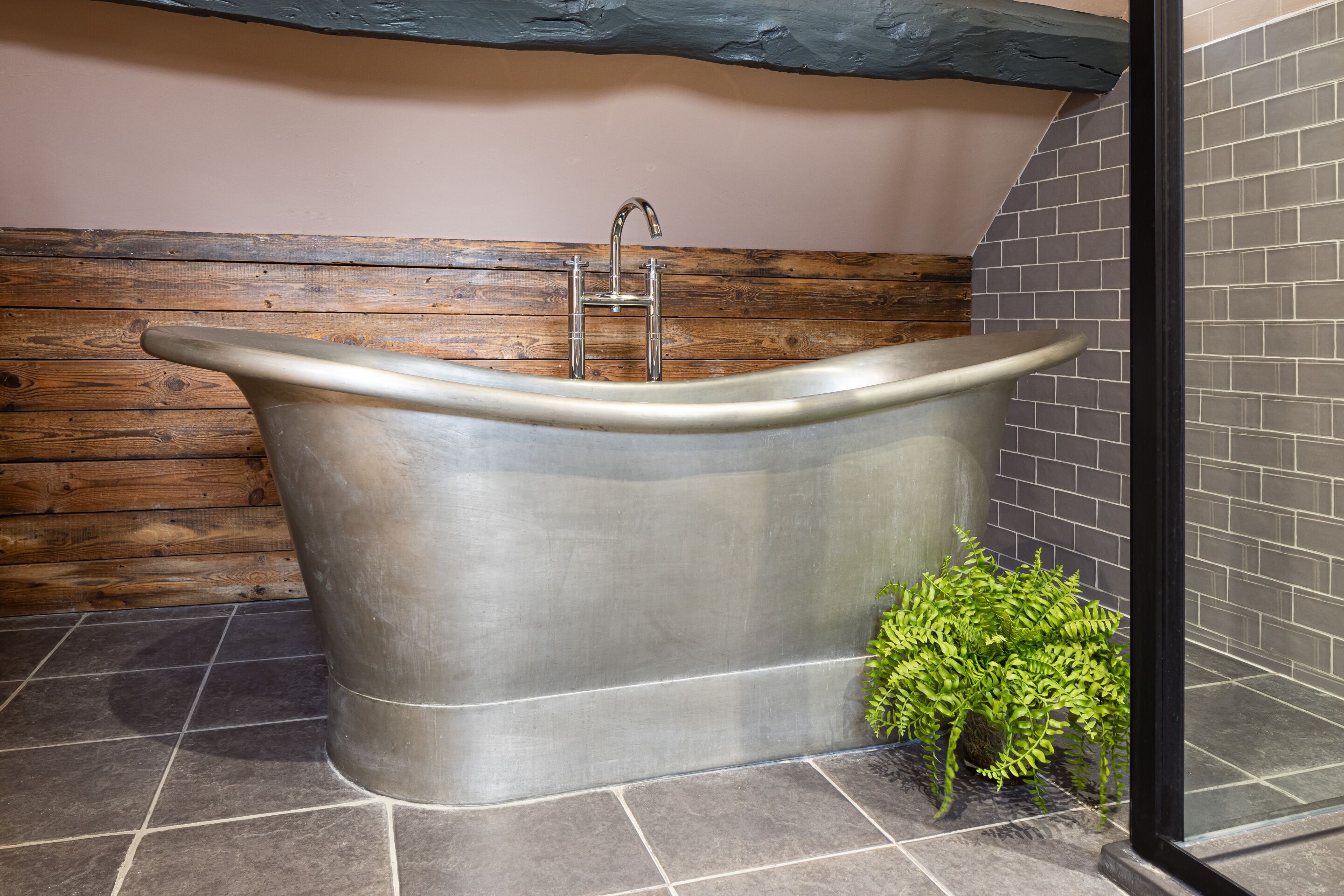 Une salle de bain moderne avec une baignoire sur pieds, un lambris en bois et un sol carrelé.