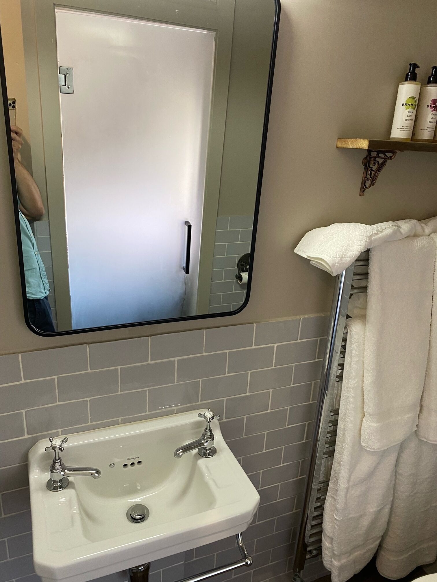 A bathroom with a white sink, a mirror, and a towel rack.
