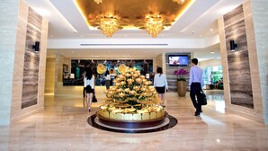 A lobby with a central floral arrangement, a chandelier, and a TV screen. - Vouk Hotel Suites, By The Blanket (George Town)