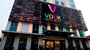 A hotel with a modern design, featuring a prominent sign for 'Vouk Hotel Suites' and a tall building in the background. - Vouk Hotel Suites, By The Blanket (George Town)