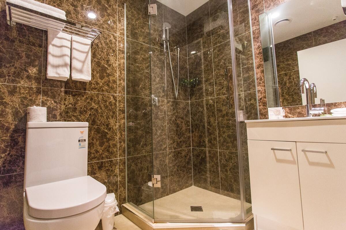 Een badkamer met een toilet, een douche met glazen wanden en een wastafel met spiegel.