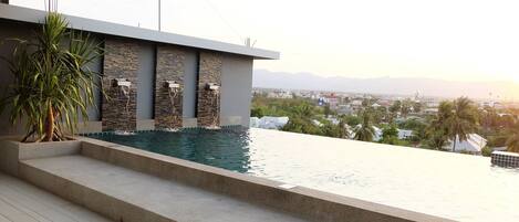 Una piscina de diseño moderno, con paredes de piedra y vistas a la ciudad de fondo.