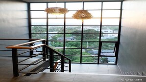 A modern interior with a staircase, large windows, and hanging wicker lamps. - C Cha-am Hotel (Cha-am)