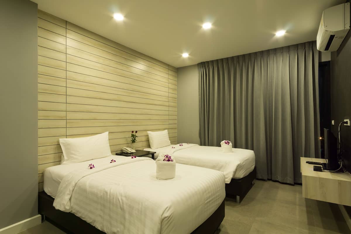 Une chambre d’hôtel avec deux lits, un bureau, une télévision et la climatisation.