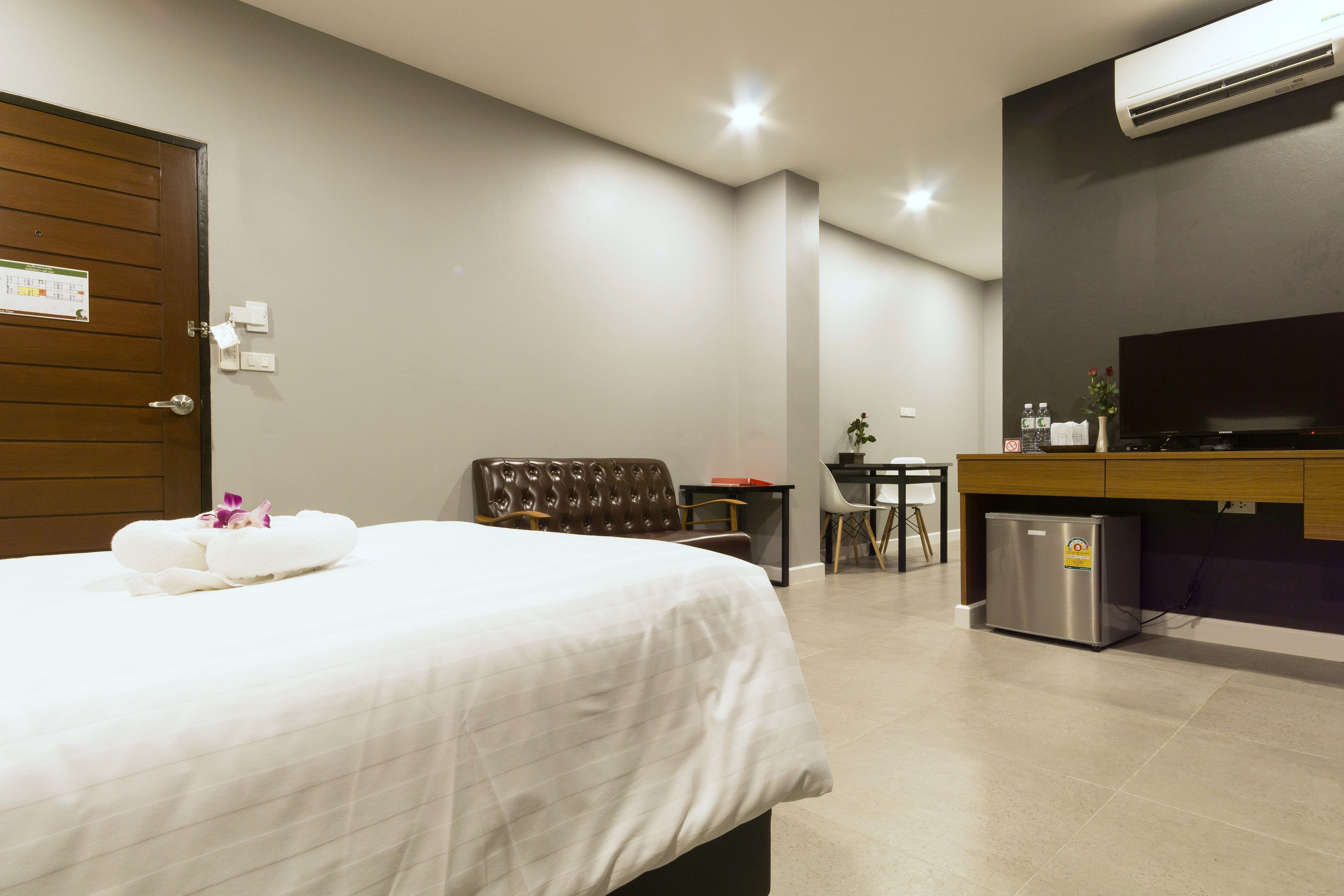 Habitación de hotel con cama, escritorio, silla, televisor y refrigerador.