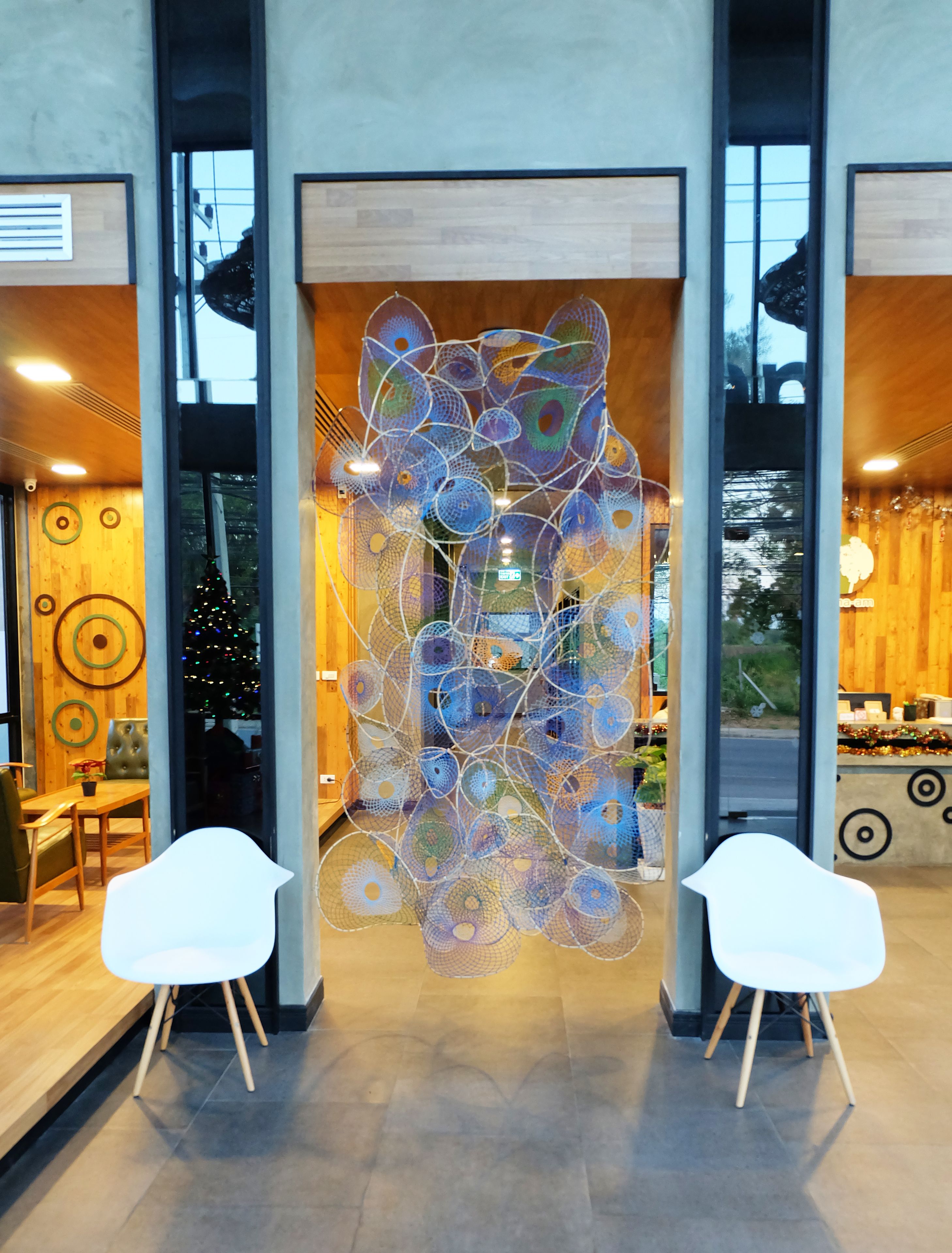 Een modern interieur met een decoratieve pauwsculptuur, twee witte stoelen en een kerstboom.