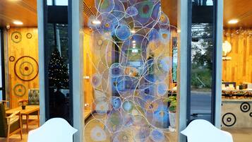 Een modern interieur met een decoratieve pauwsculptuur, twee witte stoelen en een kerstboom.