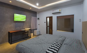 A modern bedroom with a bed, a desk, a television, and an air conditioning unit. - 88 Fine Hotel (Phunphin)