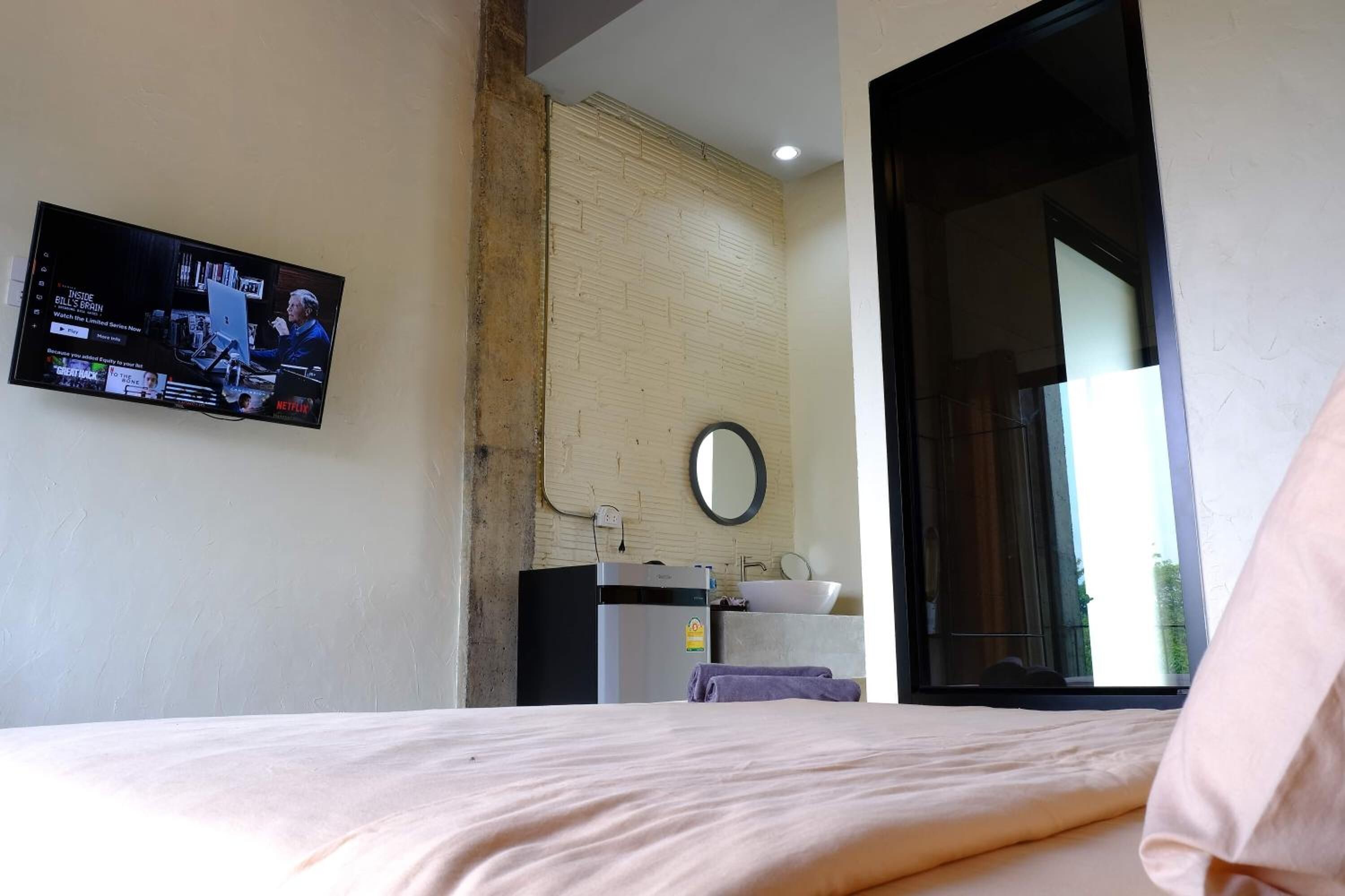 A hotel room with a bed, a television mounted on the wall, a sink, and a mirror.