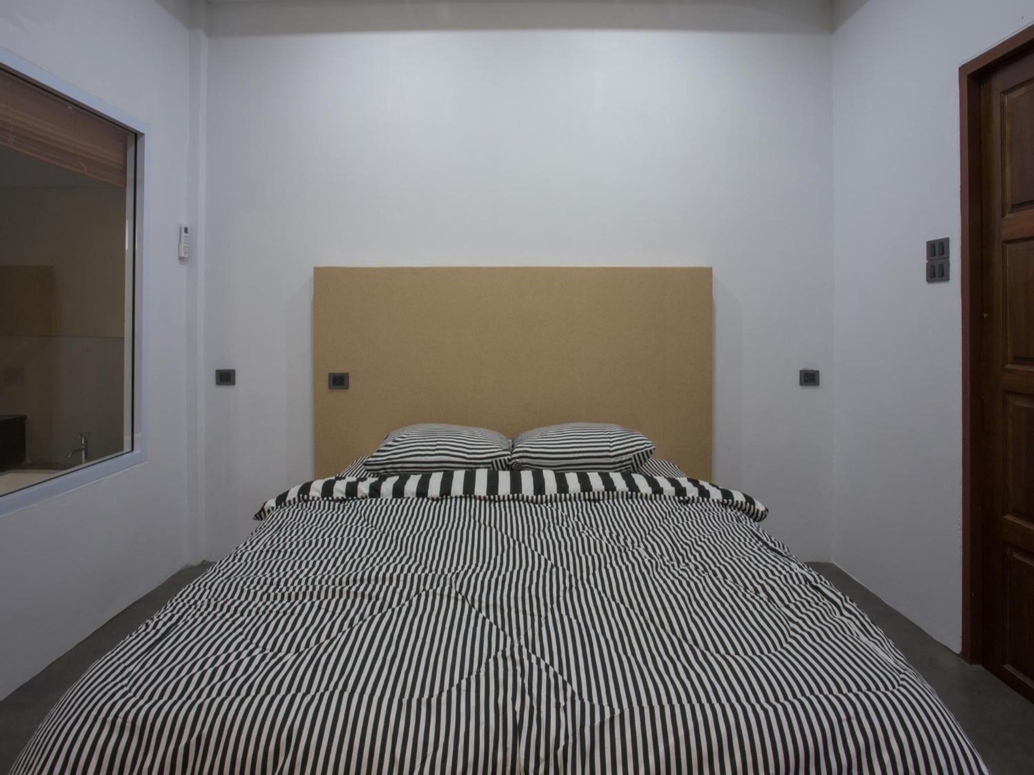 A bedroom with a bed, a headboard, and a wooden door.