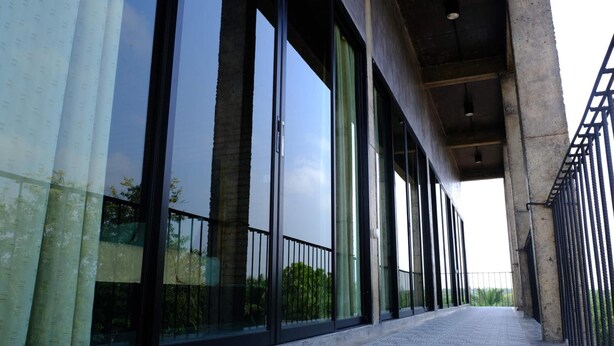 A corridor with large windows and a metal railing. - 88 Fine Hotel (Phunphin)