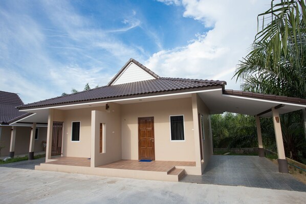 A single-story house with a tiled roof, a front porch, and a small garden area.