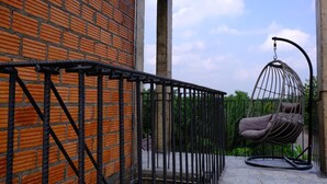 A brick wall, a metal railing, and a hanging chair on a balcony. - 88 Fine Hotel (Phunphin)