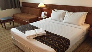Une chambre d’hôtel avec un grand lit, une table de chevet, une lampe et un petit coin salon.