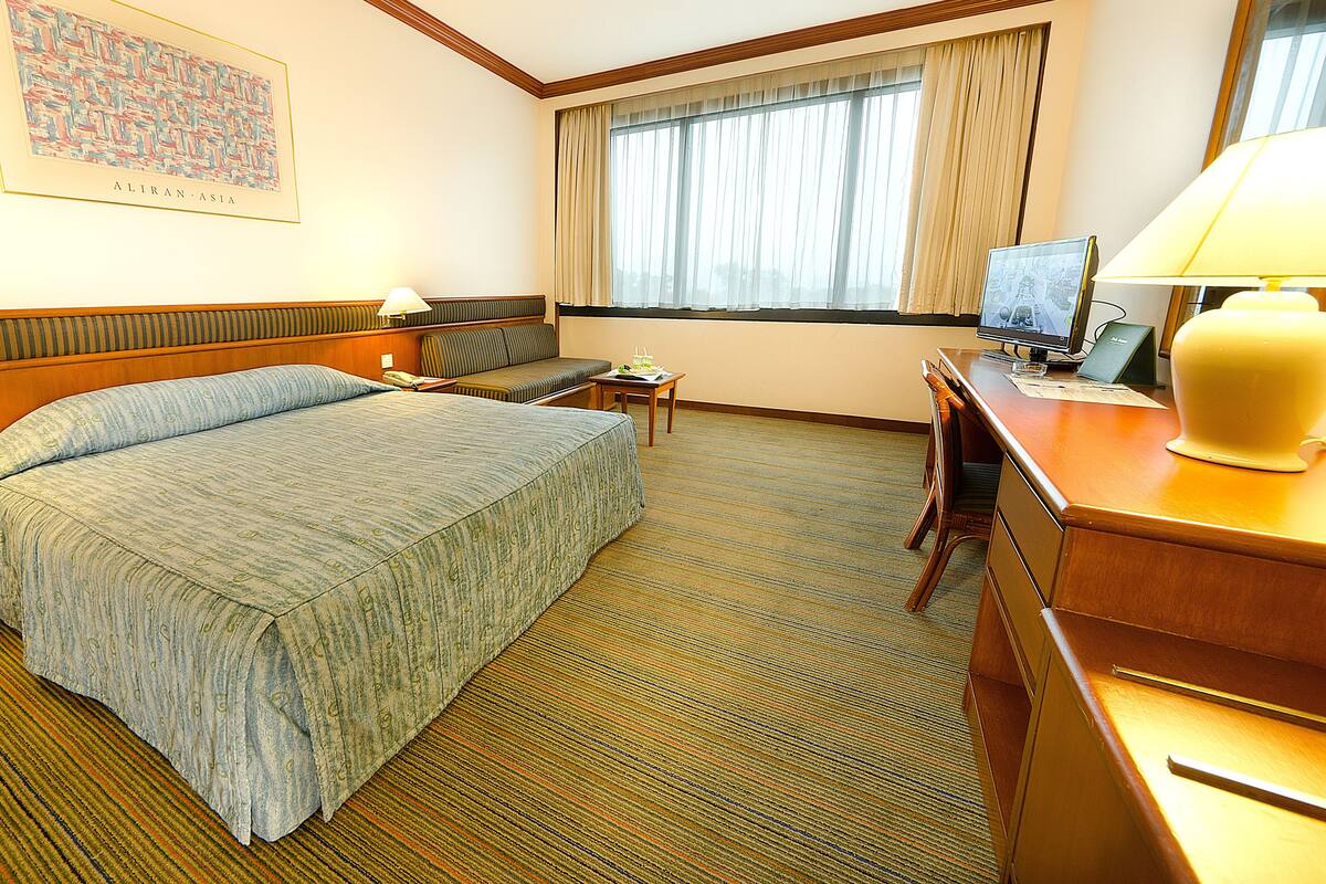 Une chambre d’hôtel équipée d’un lit, d’un bureau, d’une chaise, d’un canapé et d’une télévision.
