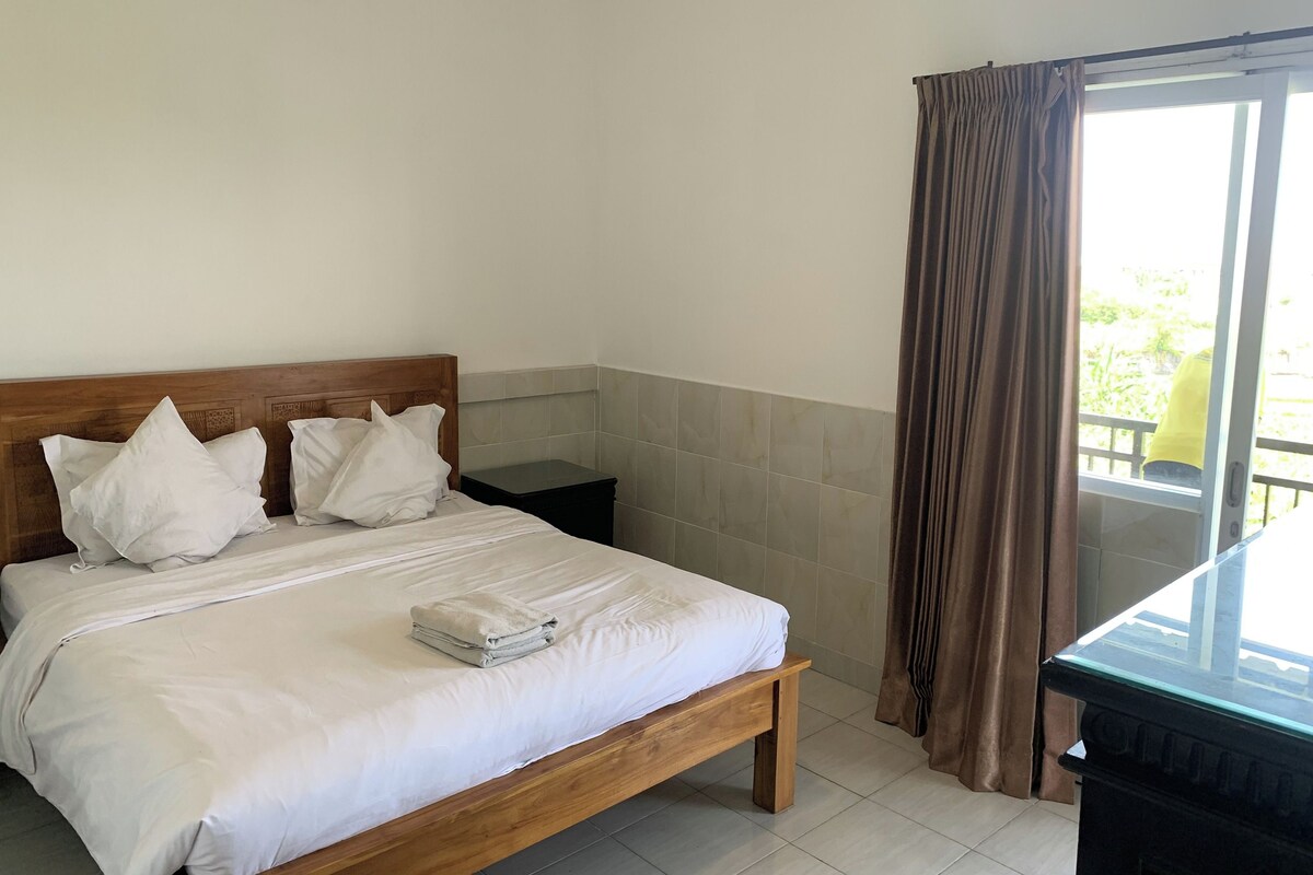 Cama bem arrumada com roupa de cama branca, cabeceira de madeira e mesa de cabeceira com abajur.