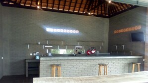 Una cocina moderna con pared de ladrillo, barra, taburetes y utensilios colgando.