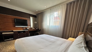 A hotel room with a large bed, a desk with a computer, a TV mounted on the wall, and a window with curtains. - Young Soarlan Boutique Hotel (Tainan)