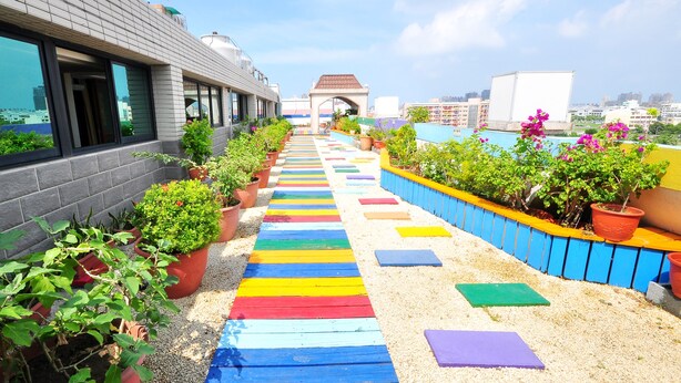 A rooftop walkway with colorful painted steps, potted plants, and a view of the cityscape. - Young Soarlan Boutique Hotel (Tainan)