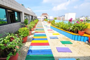 Un paseo en la azotea con escalones pintados de colores, plantas en macetas y vistas de la ciudad.