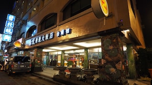 A hotel entrance with a large sign, outdoor seating area, and potted plants. - Young Soarlan Boutique Hotel (Tainan)